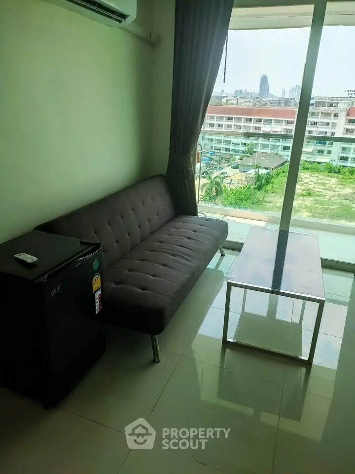 Modern living room with city view, featuring a sleek sofa and glass coffee table.
