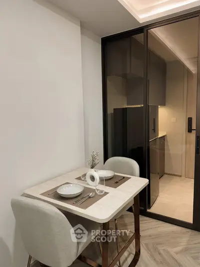 Modern dining area with elegant table setting adjacent to a sleek kitchen with glass partition.