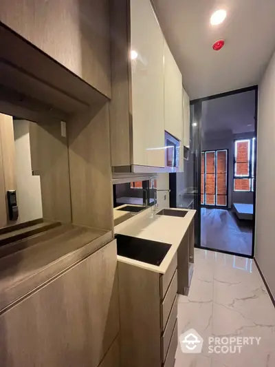 Modern compact kitchen with sleek cabinetry and glass partition in stylish apartment.