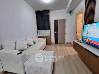 Modern living room with cozy sofa and flat-screen TV, featuring sleek wooden flooring and minimalist decor.