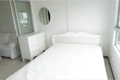 Bright and airy bedroom with white furniture and large windows offering natural light.