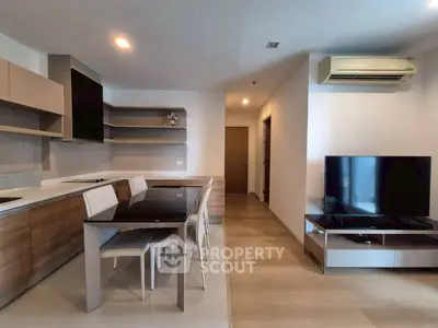 Modern open-layout living room with sleek kitchen and dining area, featuring contemporary furniture and neutral tones.