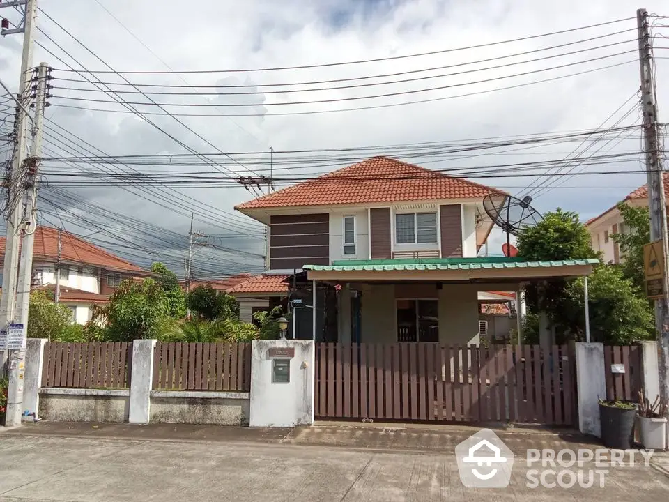 Charming two-story house with red roof and fenced yard in suburban neighborhood.