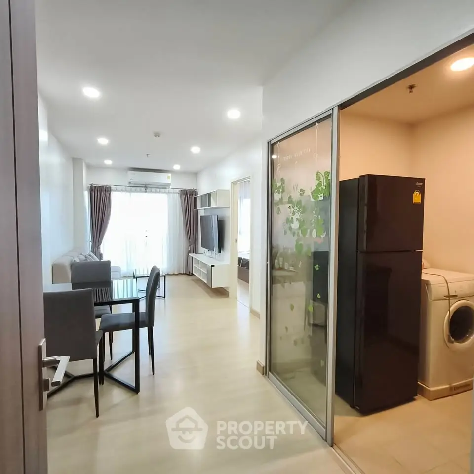 Modern apartment interior with open living and dining area, featuring sleek furniture and natural light.