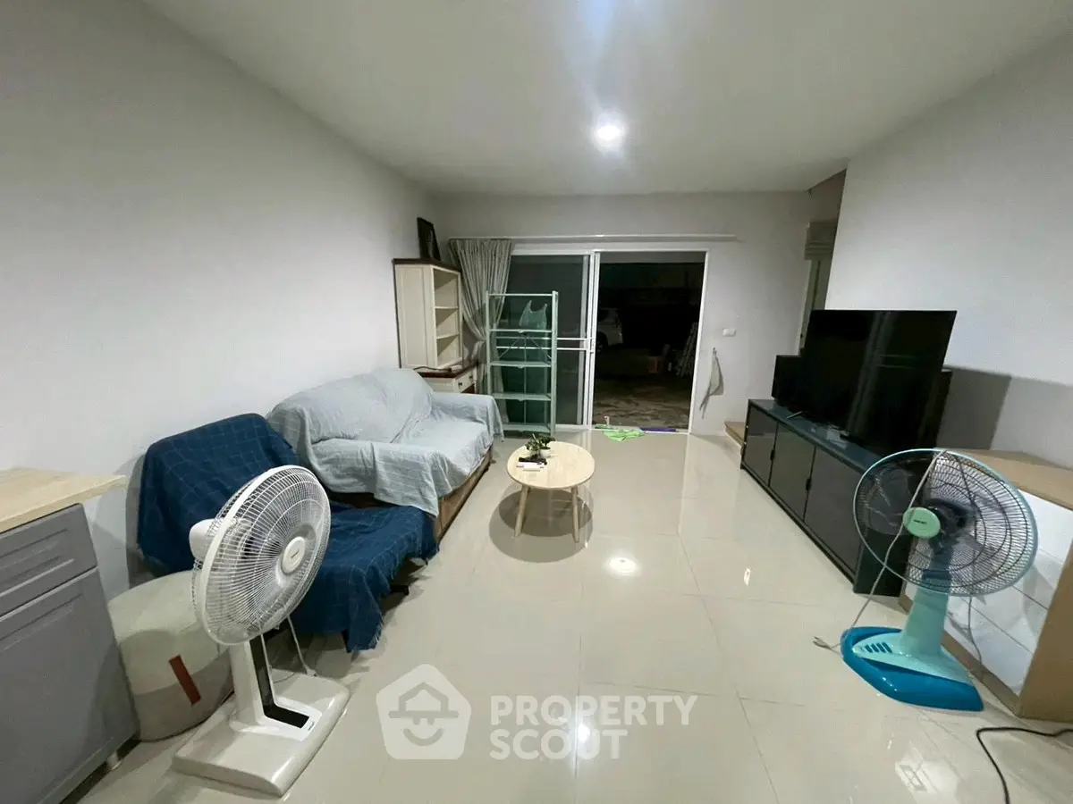 Spacious living room with modern furnishings and large TV, perfect for relaxation and entertainment.