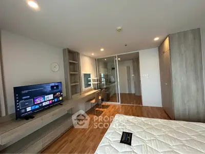 Modern bedroom with wooden flooring, TV, and study area in a stylish apartment.