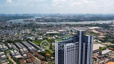 Stunning aerial view of modern high-rise building with cityscape and river in the background.