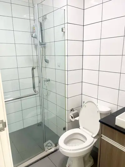 Modern bathroom with glass shower and sleek fixtures in contemporary apartment.