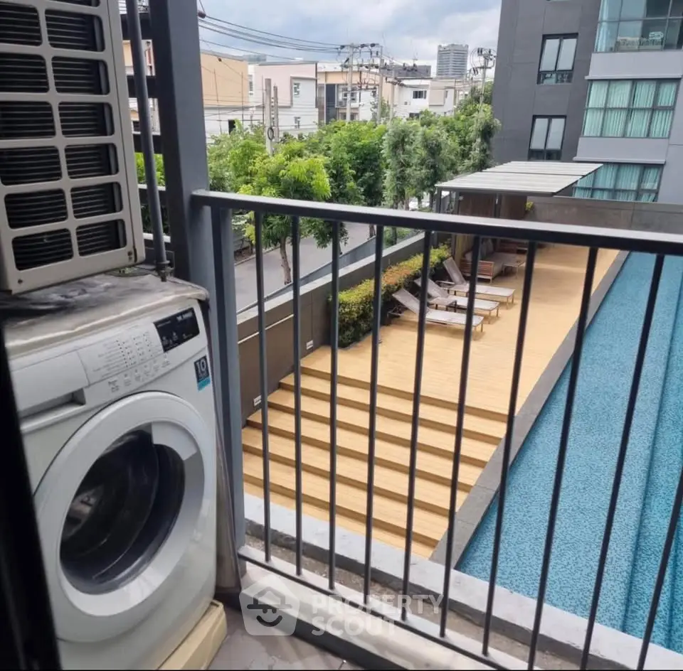 Modern apartment balcony with washing machine overlooking a stylish pool area.