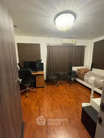 Cozy study room with wooden flooring, desk, and seating area, ideal for productivity and relaxation.