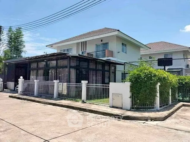 Charming two-story house with a spacious corner lot and lush greenery, perfect for family living.