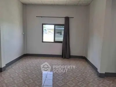 Spacious empty room with tiled floor and window, perfect for customization.