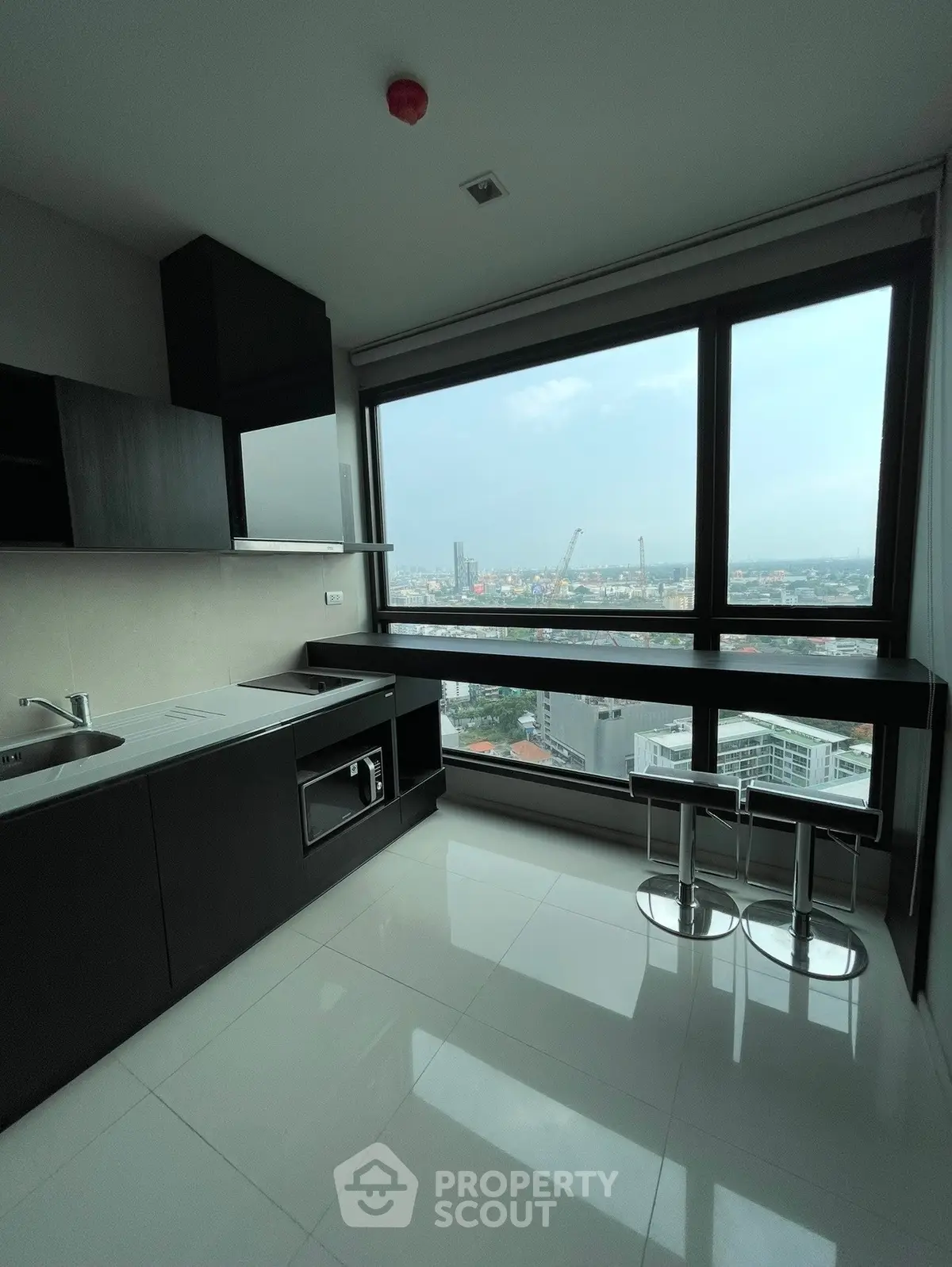 Modern kitchen with stunning city view, featuring sleek cabinetry and breakfast bar seating.