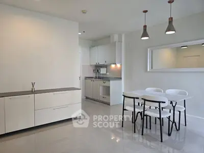 Modern kitchen and dining area with sleek white cabinets and contemporary lighting.