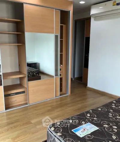 Spacious bedroom with wooden flooring and mirrored wardrobe in modern apartment.