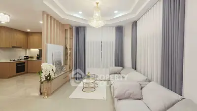 Luxurious living room with elegant chandelier and modern kitchen in open layout