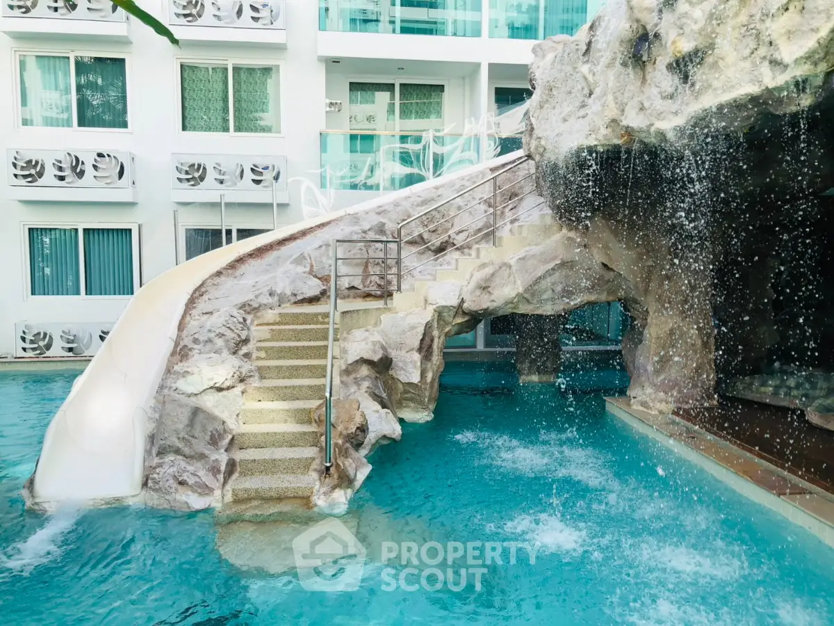 Luxurious pool area with waterfall and slide in modern residential complex.