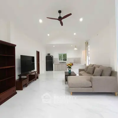 Spacious modern living room with open kitchen, elegant furniture, and ceiling fan.