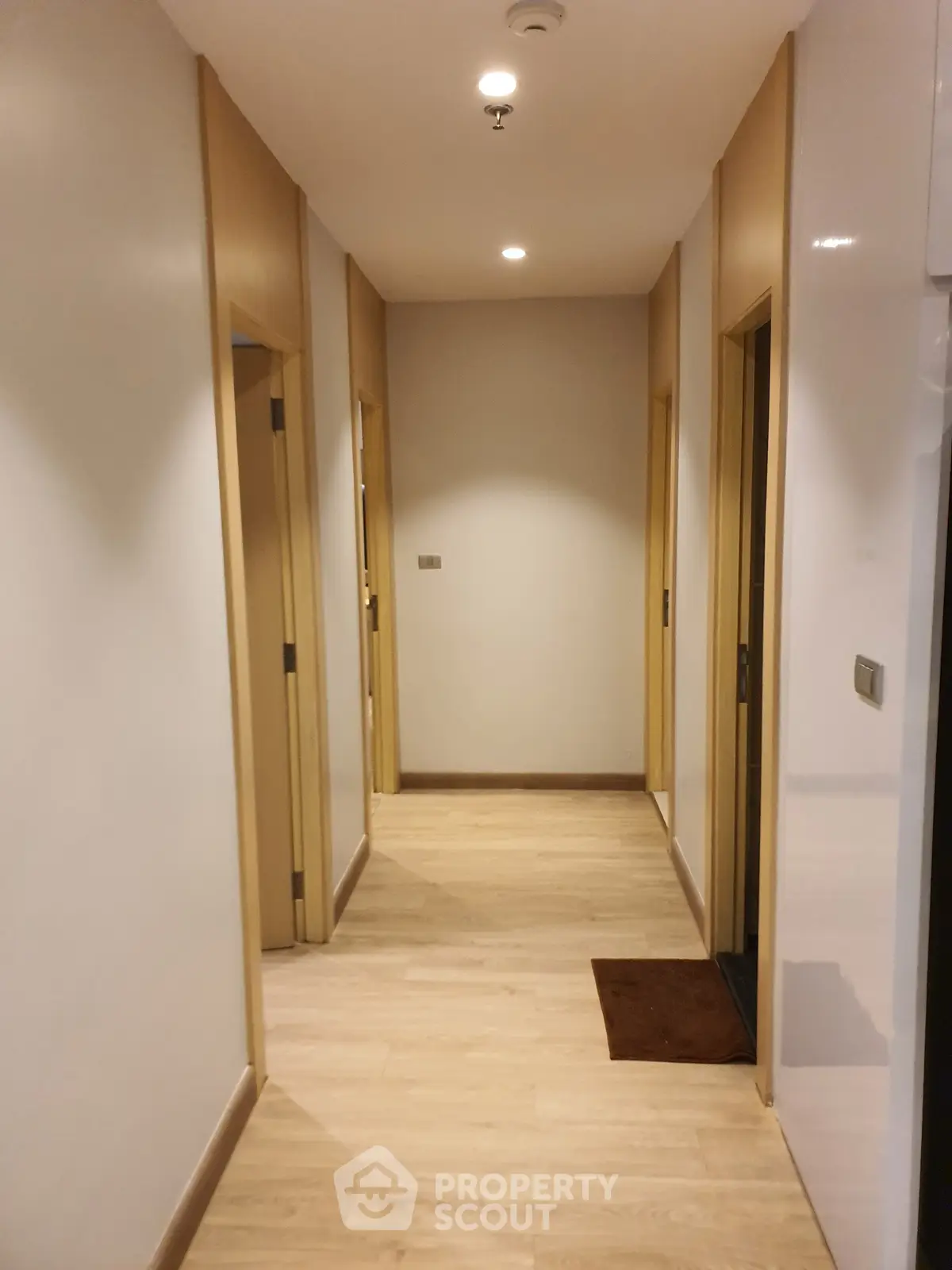 Modern apartment hallway with wooden flooring and recessed lighting