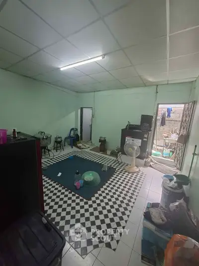 Spacious living room with checkered floor tiles and open access to outdoor area.