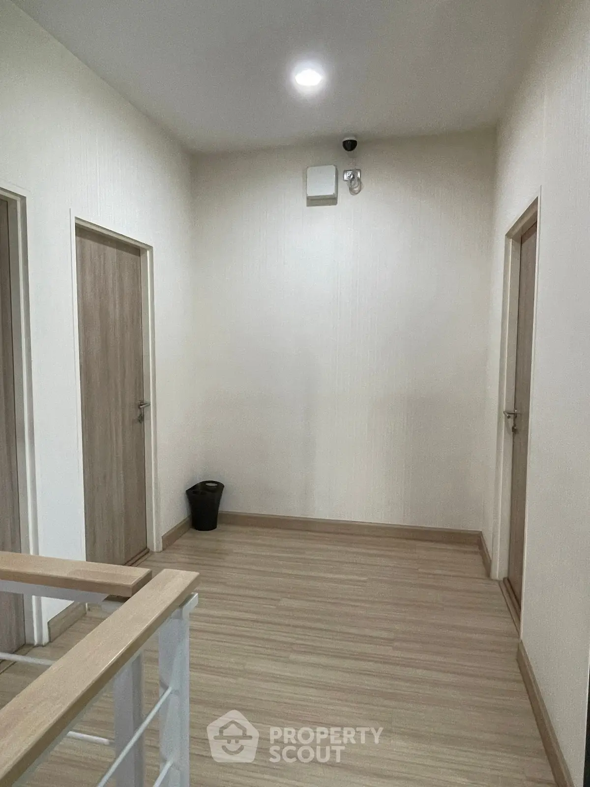 Modern hallway with wooden flooring and multiple doors in a residential building.