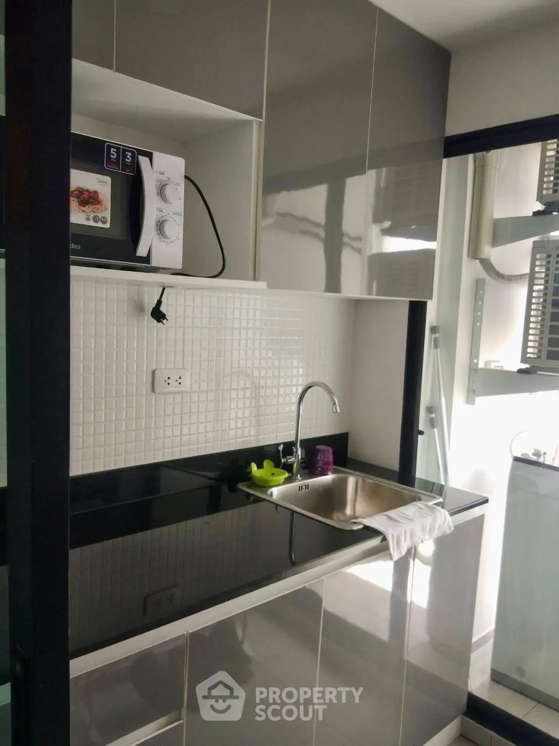 Modern kitchen with sleek cabinetry and built-in microwave, featuring a compact design and glossy finishes.