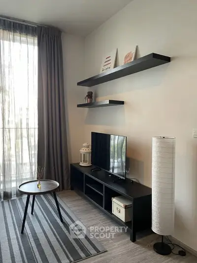 Modern living room with sleek furniture and natural light, featuring a stylish TV stand and decorative shelves.