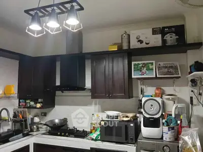 Modern kitchen with dark cabinets and appliances, featuring a gas stove and microwave.