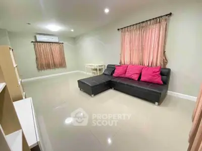Spacious living room with modern black sofa and pink curtains, perfect for relaxation and entertainment.