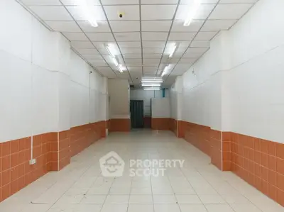 Spacious commercial space with tiled flooring and fluorescent lighting, ideal for retail or office use.