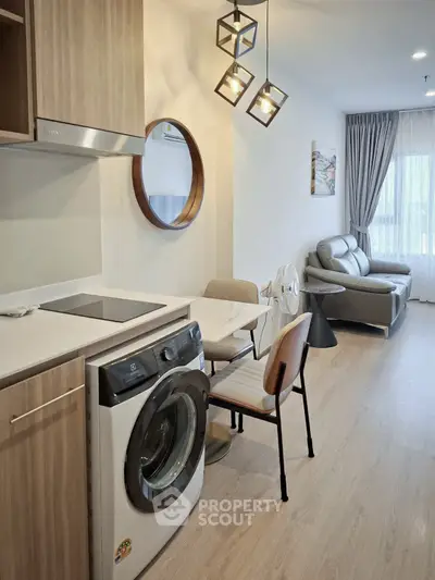 Modern open-plan living room with stylish furniture and in-unit washing machine, perfect for urban living.