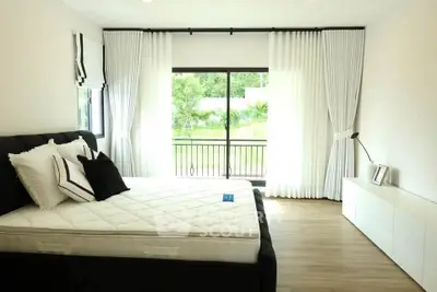 Spacious bedroom with large window and scenic view, featuring modern decor and elegant curtains.
