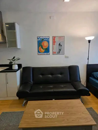 Modern living room with sleek black sofa, stylish posters, and cozy lighting, perfect for urban living.