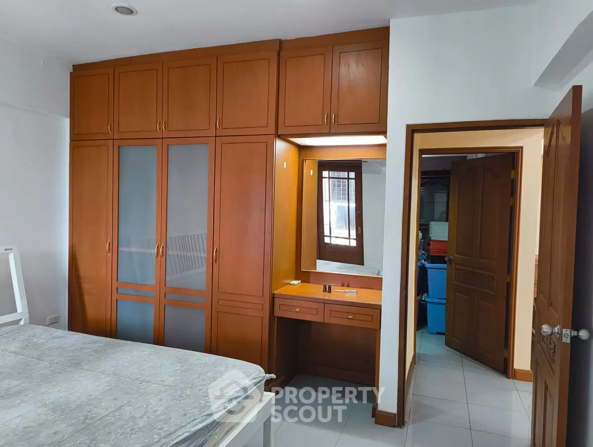 Spacious bedroom with built-in wooden wardrobe and vanity area
