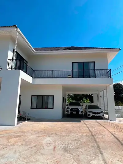 Modern two-story house with spacious driveway and carport under clear blue sky.