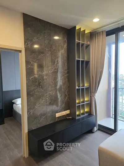 Modern living room with sleek shelving and marble accent wall, featuring floor-to-ceiling windows and city view.