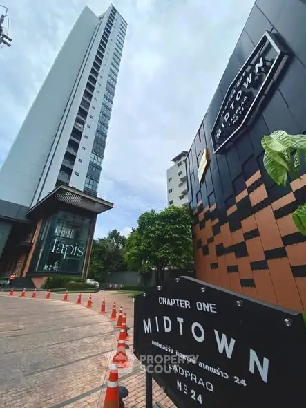 Modern high-rise building with sleek design and prominent signage in urban setting.