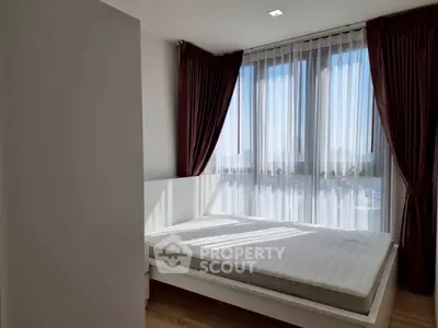 Modern bedroom with large windows and elegant curtains, featuring a minimalist bed frame and natural light.