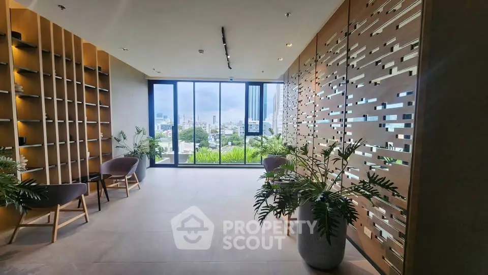 Modern building lobby with stylish decor and city view through large windows.