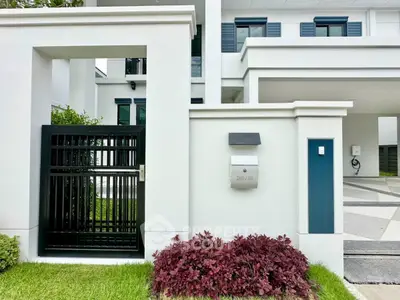 Modern white house exterior with sleek black gate and manicured lawn