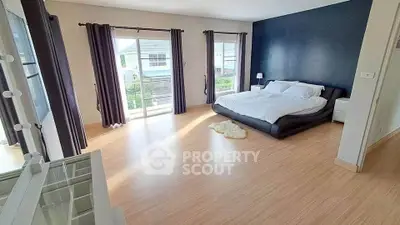 Spacious bedroom with modern decor and large windows for natural light.