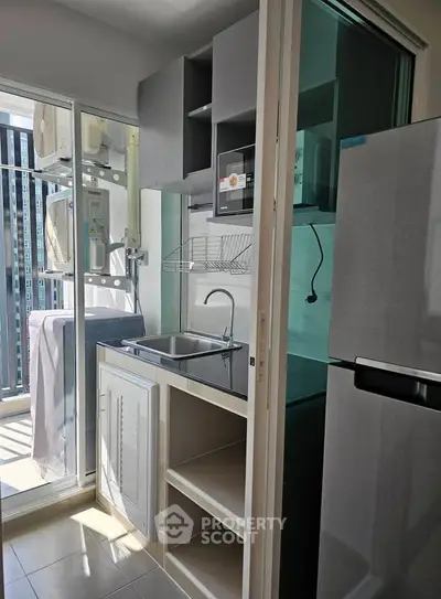 Compact kitchen with modern appliances and balcony view in urban apartment