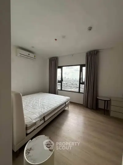 Spacious bedroom with city view, featuring a large window, bed, and modern furnishings.