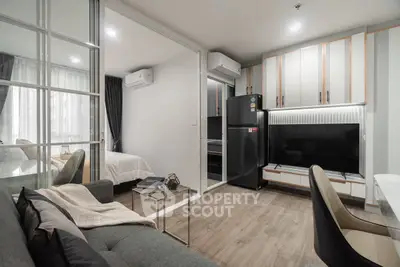 Modern open-plan living room with sleek kitchen and cozy bedroom view.