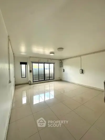 Spacious empty living room with large windows and tiled flooring, ready for customization.