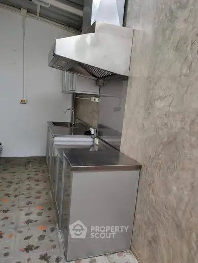 Modern industrial-style kitchen with stainless steel appliances and concrete walls.