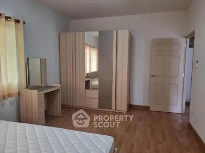 Spacious bedroom with wooden flooring and large wardrobe