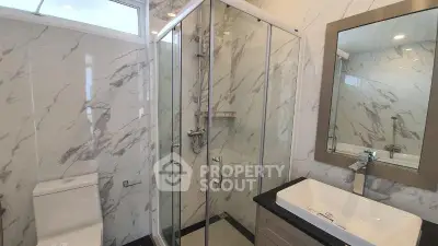 Luxurious modern bathroom with marble walls and glass shower enclosure