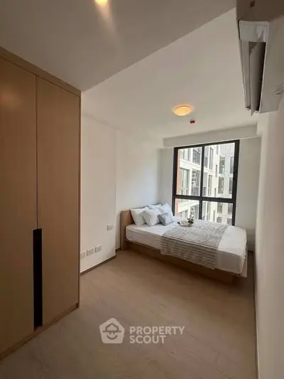Modern bedroom with large window and wooden wardrobe in a stylish apartment.