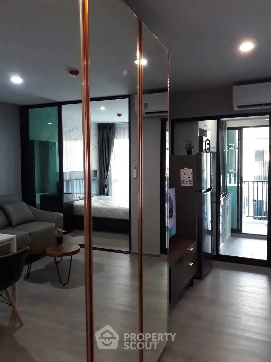 Modern apartment interior with open layout, featuring living room, bedroom, and kitchen with balcony access.